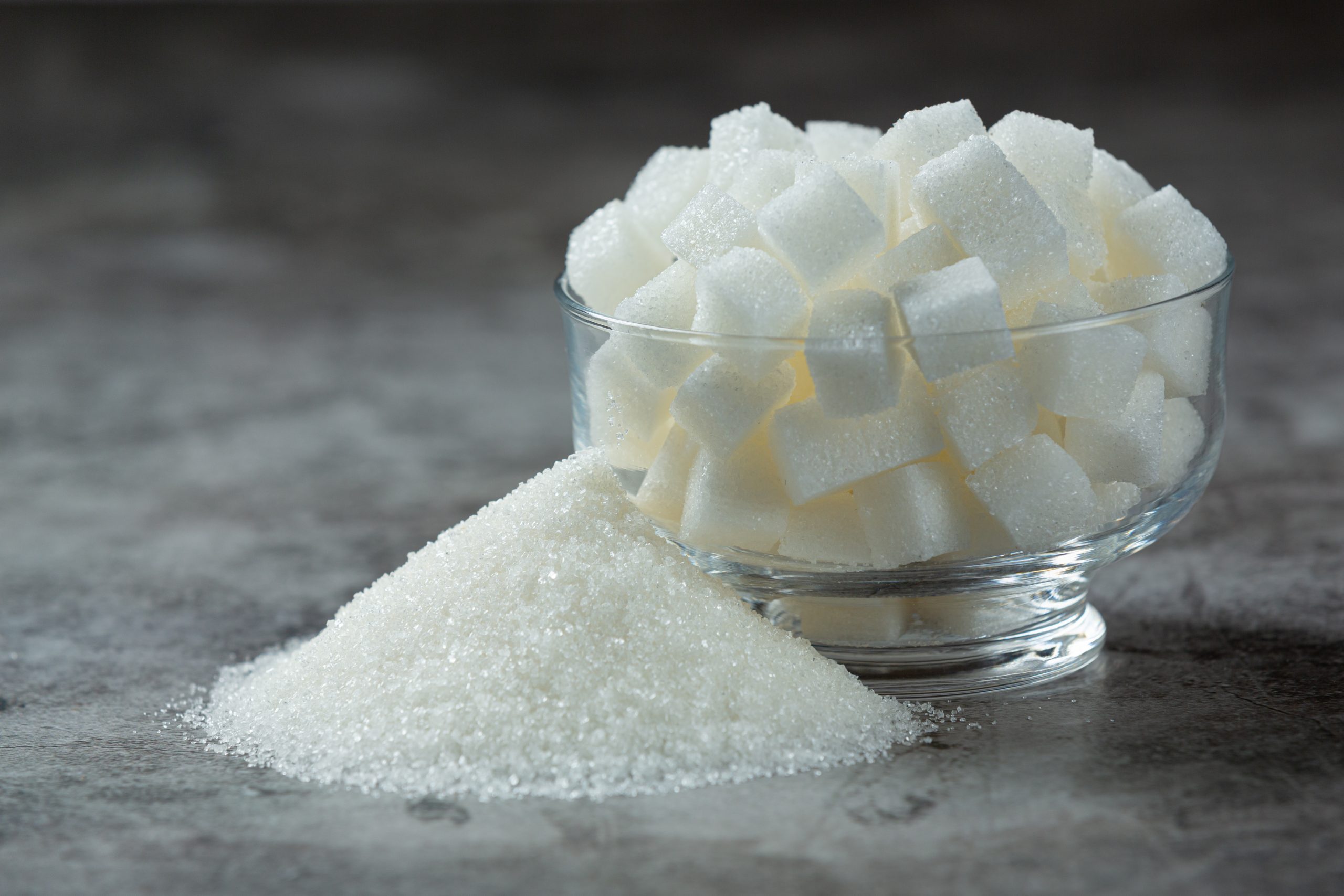 World diabetes day;Sugar cubes in a glass bowl on dark floor World diabetes day;
Sugar cubes in a glass bowl on dark floor